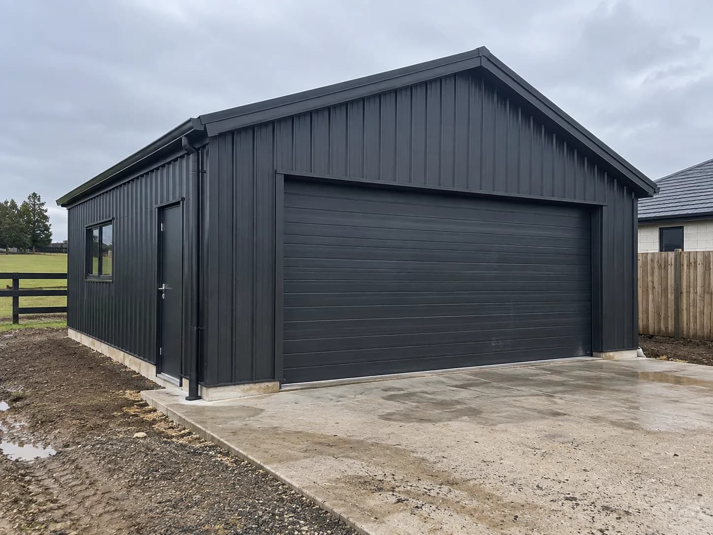 A double garage built by Finer Builds with dark cladding and a roller door.